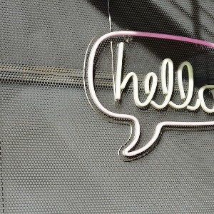 Neon sign of a speech bubble around the word 'hello'